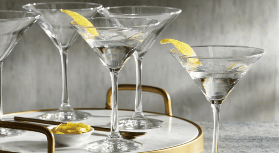 Copas de martini de cristal con twist de limón sobre una bandeja de mármol